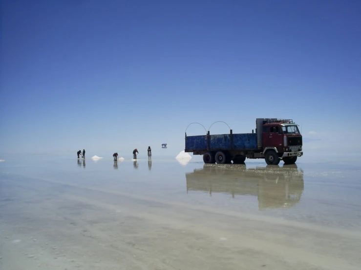 a truck driving on the beach in front of people