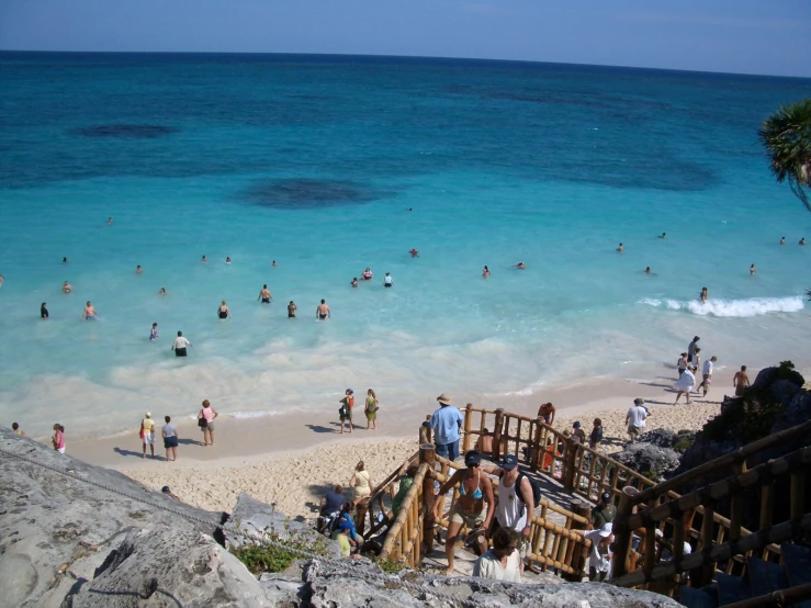 people are swimming on a beach with clear water