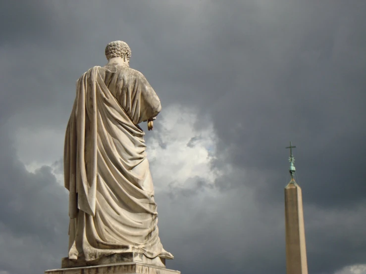 a very tall statue sitting below a cloudy sky