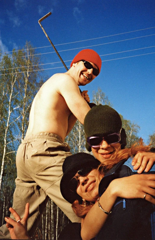 three people, one with a red hat, are smiling for the camera