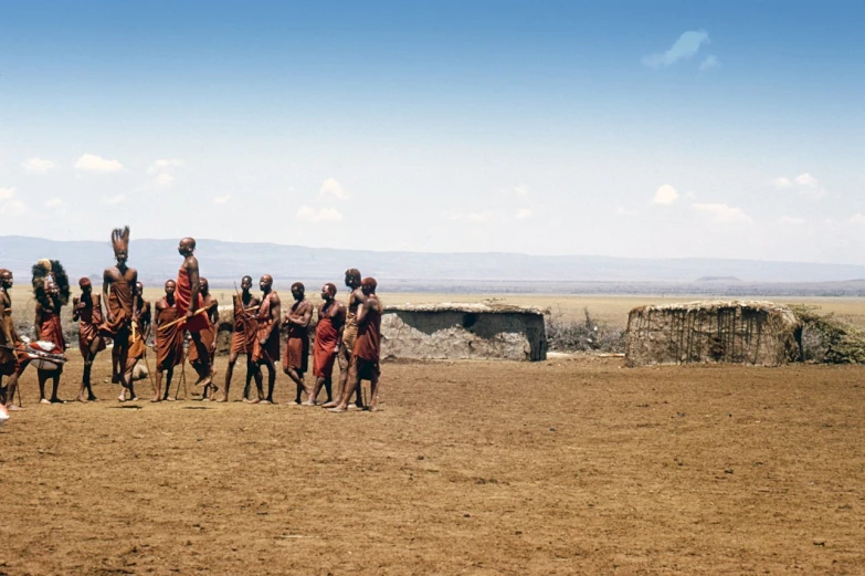 men wearing costumes and with headdreses stand with horses in the desert