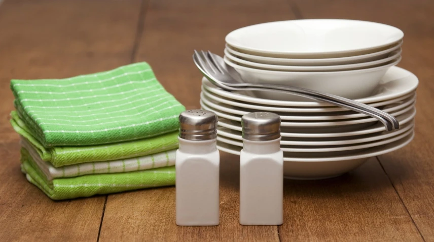 a stack of dishes and a fork on top of a wooden table