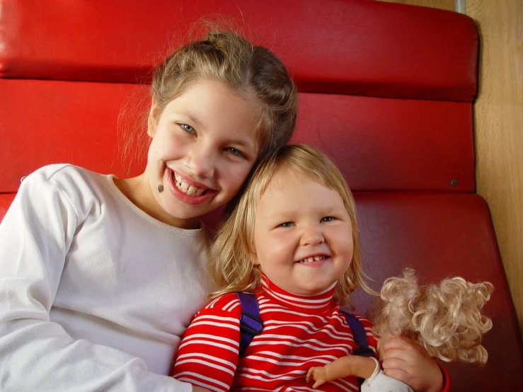 two children, one girl holding a teddy bear and smiling