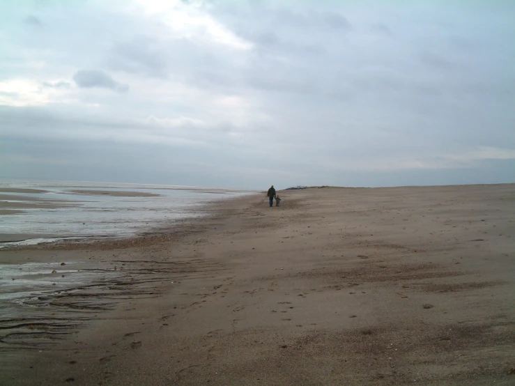 a man walking on top of a sandy beach