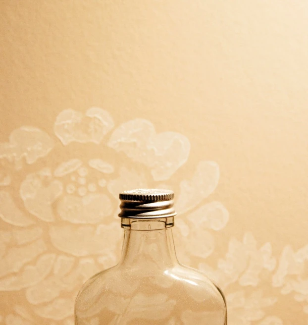 a clear bottle with a black lid sitting in front of a wall