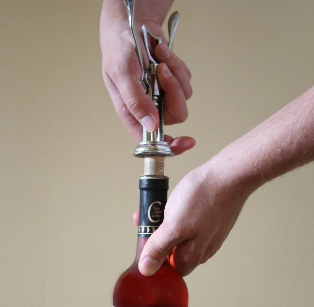 a person is tying a wine bottle with a pair of scissors