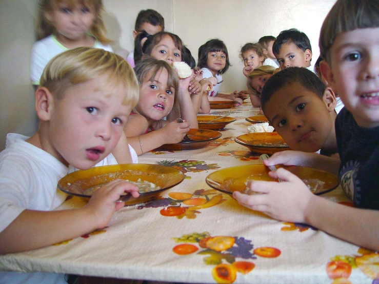 young children eating cake at table during meal