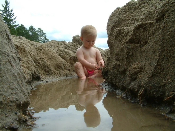 a young child is playing in the water near rocks