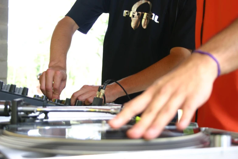 two men playing with a dj equipment on an outdoor patio