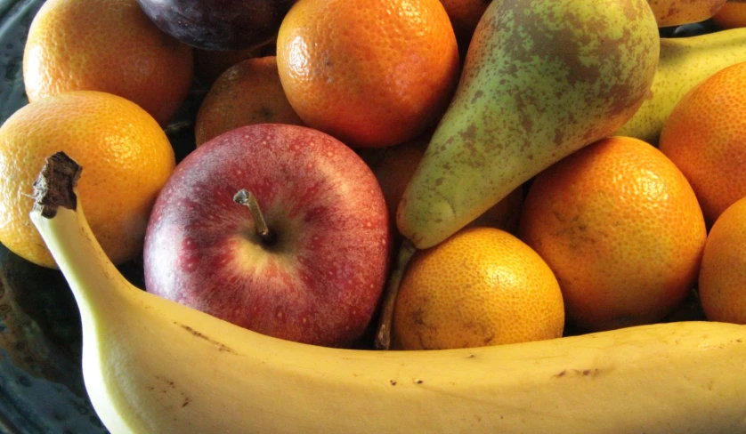 a bowl full of assorted fruits and one banana