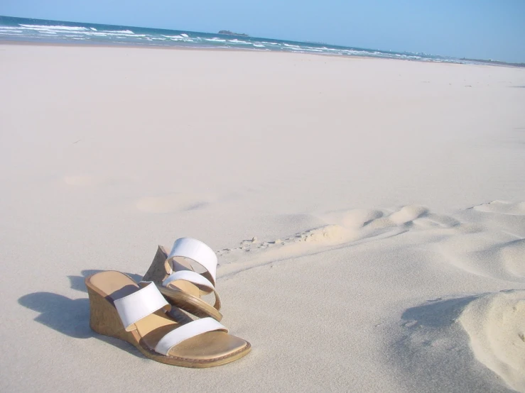 a pair of white slippers are laying on the sand