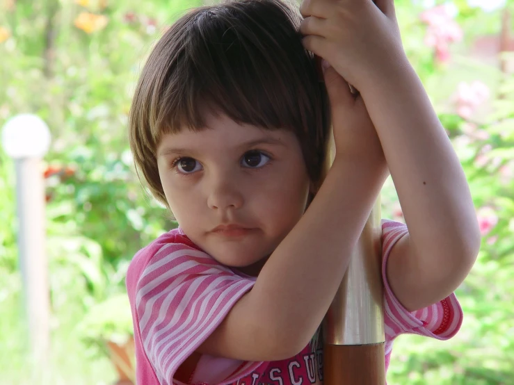 a little girl holding onto the top of a chair