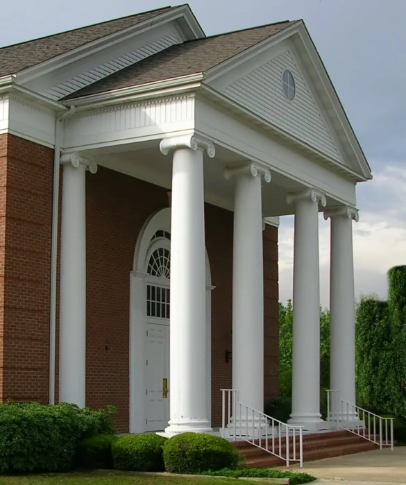 a house with columns on each side and a clock on the top