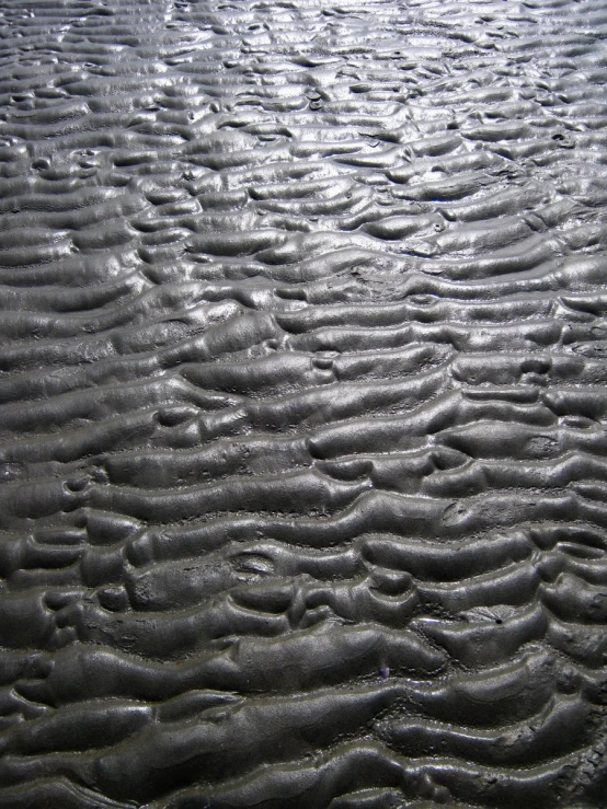 a close up of sand with ripples and water