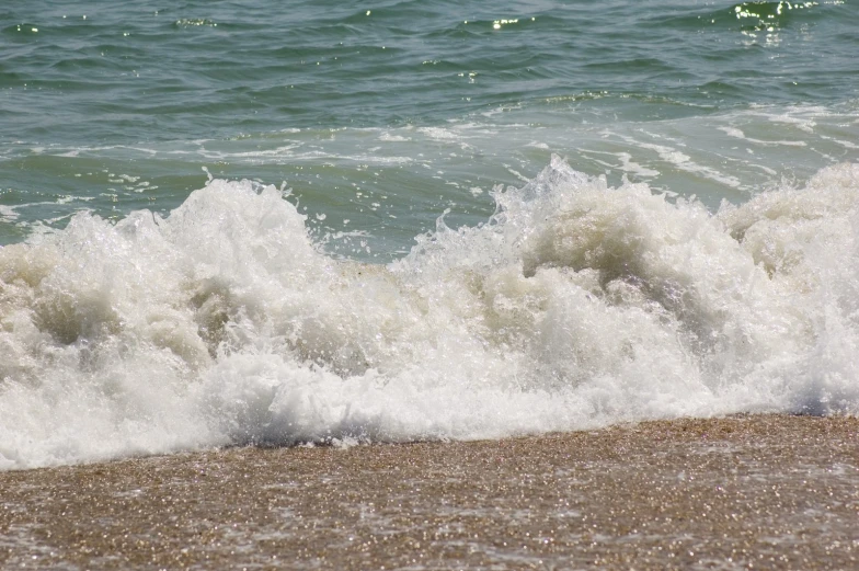 water splashing onto the beach with a wave coming in