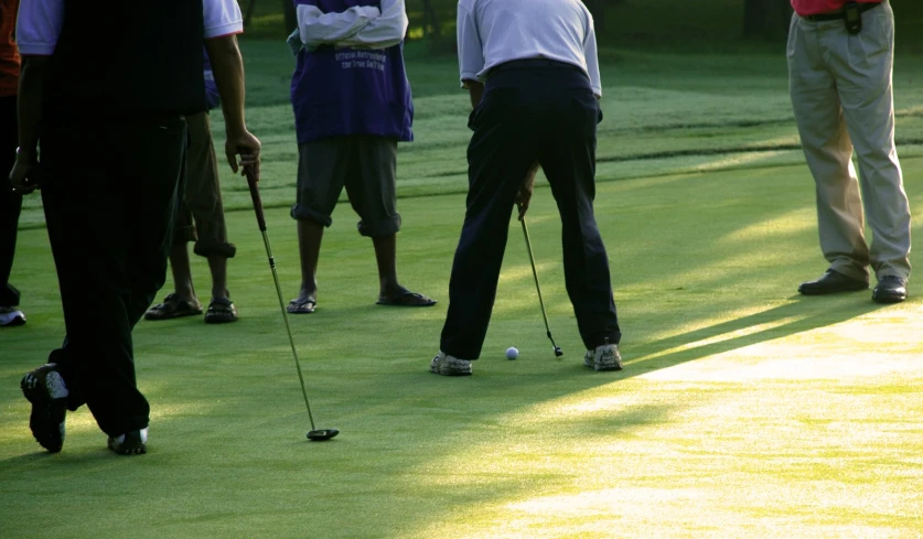 golfers standing around a green with their feet up