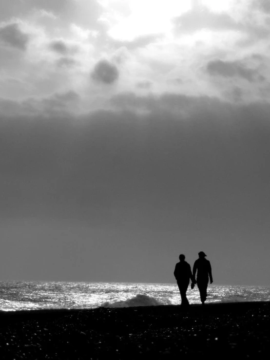 two people walking along the beach holding surfboards