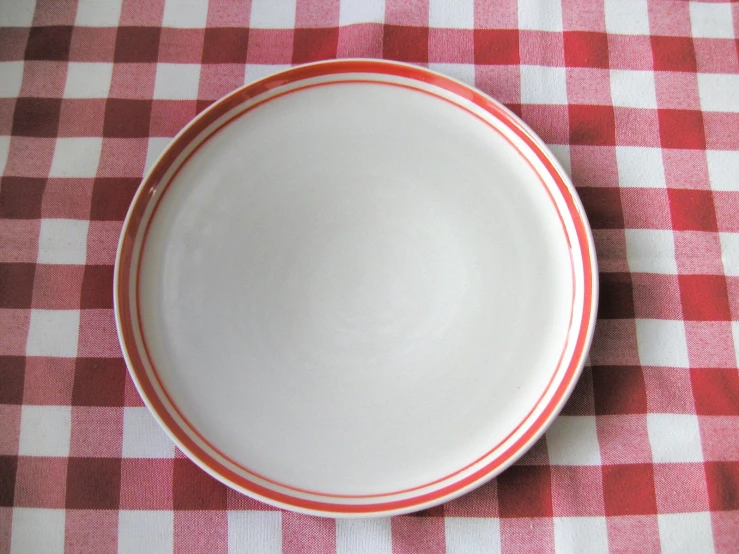 white dish with red stripe on top of a red and white checkered table cloth