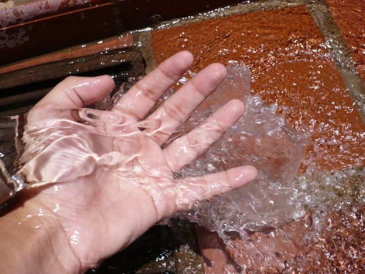 hand and hand being washed in water near orange wall