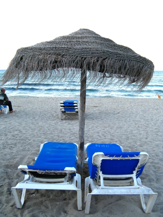 two beach chairs sitting next to an umbrella
