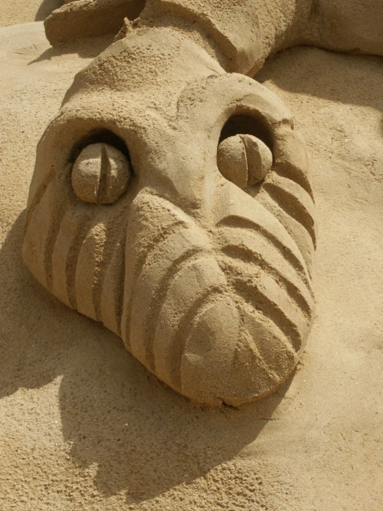an animal sand sculpture sits in the sun