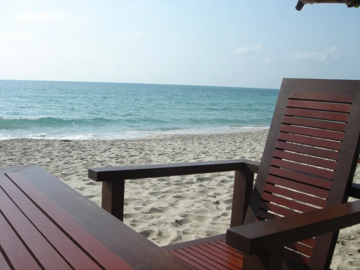 two beach chairs sit on the shore near a body of water