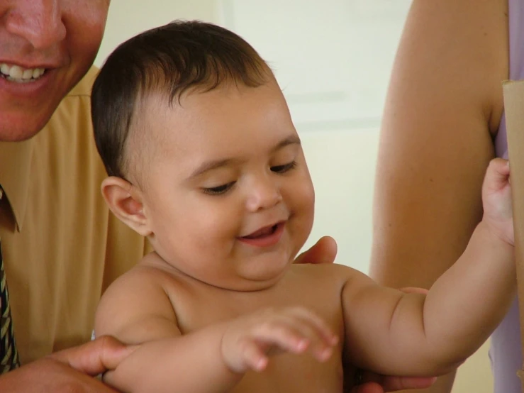 man holding his infant while another baby smiles