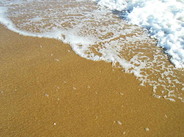 a wave coming up from the shore on the beach