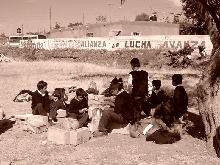 boys sitting on a sand ground with cardboards