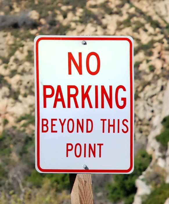 a red and white sign with a no parking beyond this point written below it