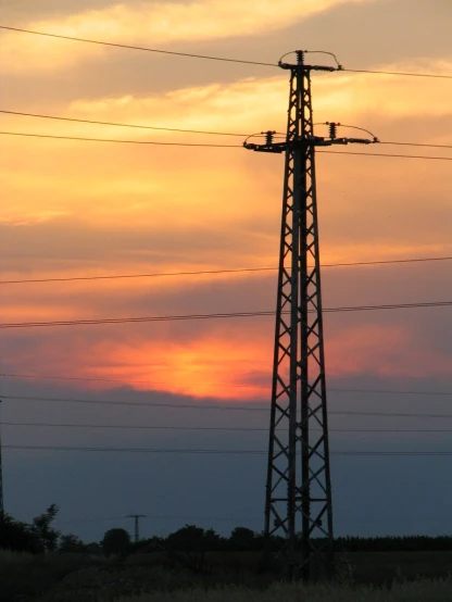 high voltage power tower in silhouette against the evening sky