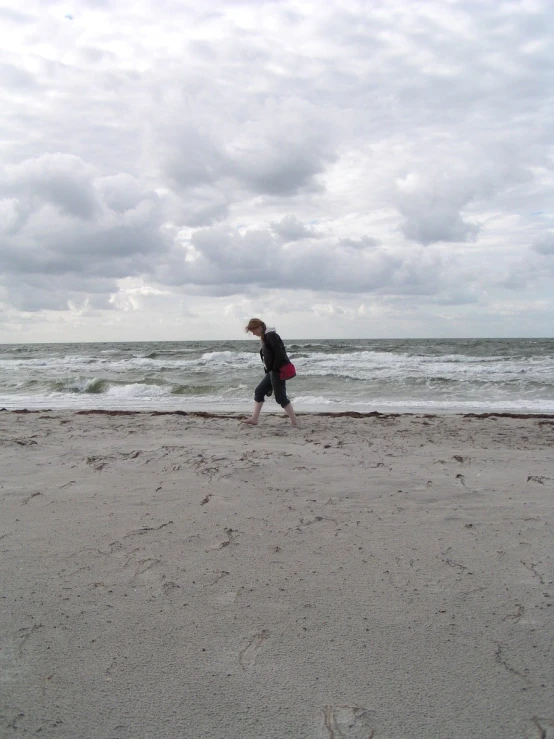 a person walking on the beach with a kite in the air