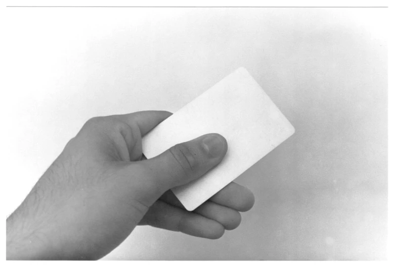 a hand holding a piece of white paper with it's end in the air