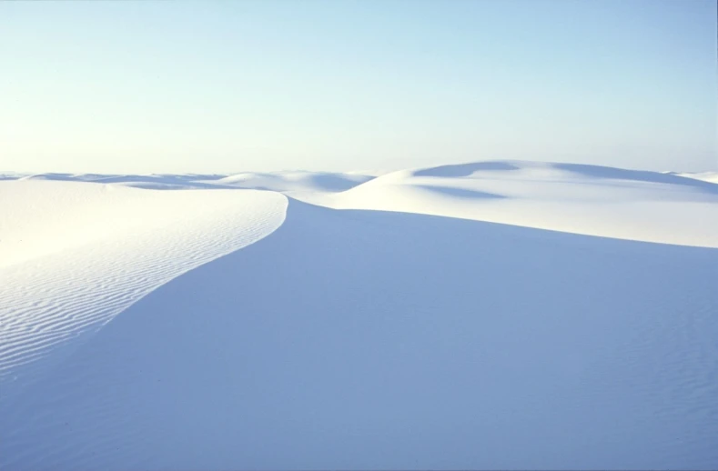 a snow covered desert with tracks in the sand