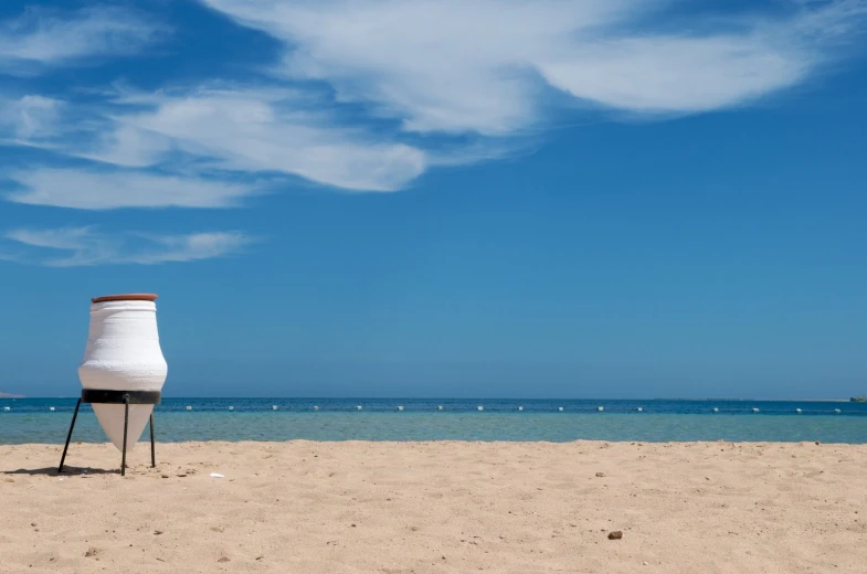 an odd shaped object sits on top of a stand on the beach