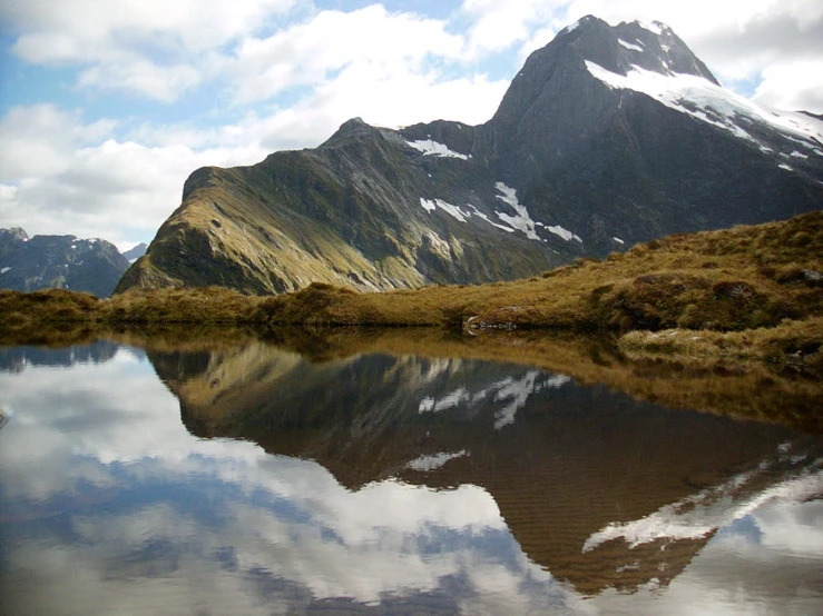 mountains surrounding a lake in the middle of a grassy area