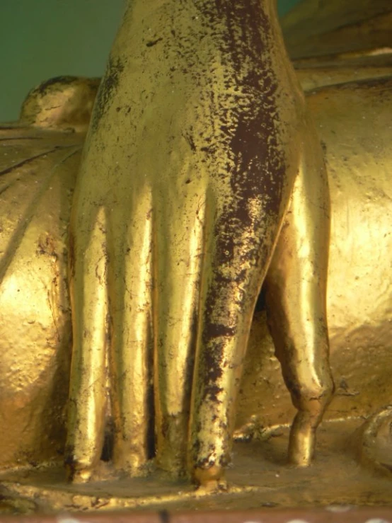 an ornate golden metal statue with the foot curled out