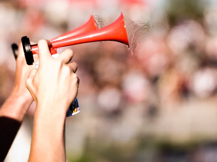 a closeup of two people using a red hand held megaphone