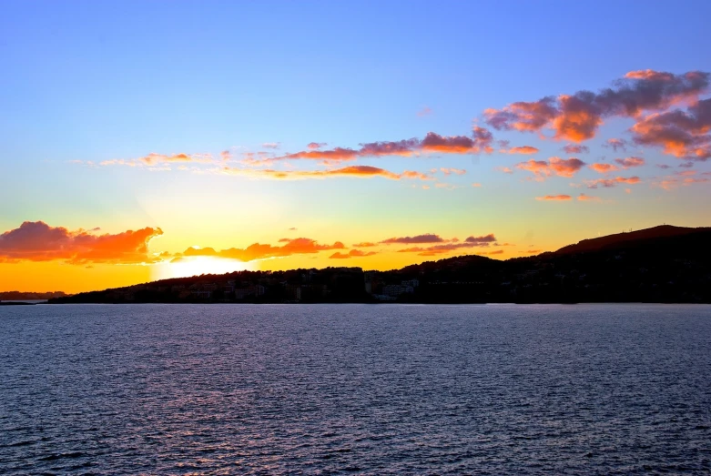 sunset with white clouds over a lake and mountains