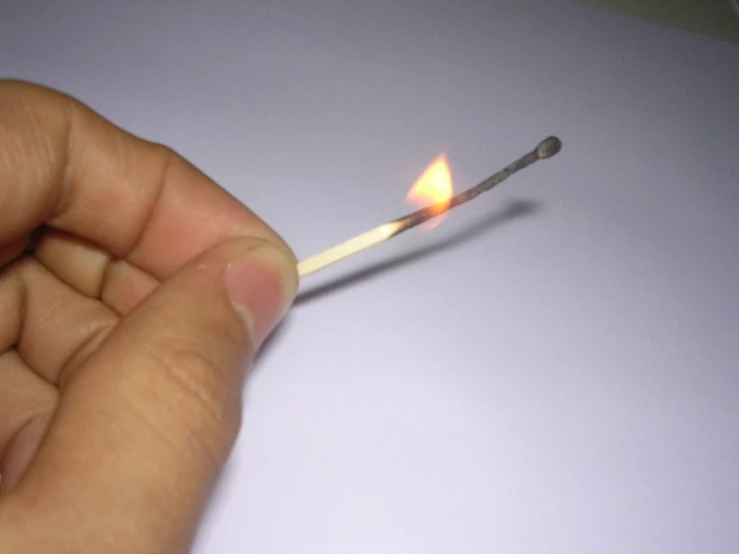 a hand is holding a match which has a small flame