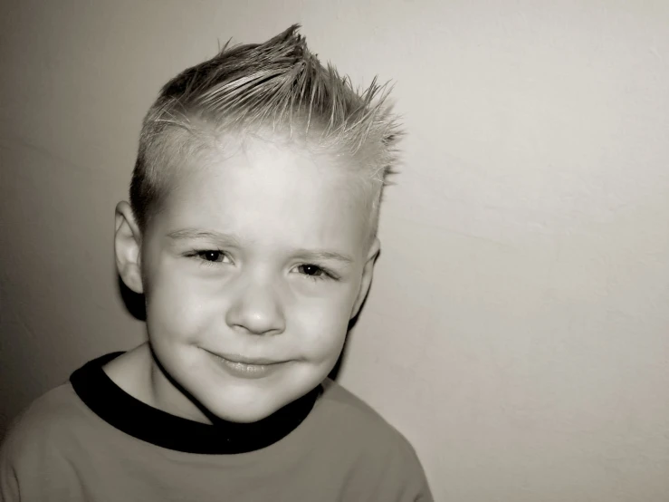 a little boy with blonde hair smiling at the camera