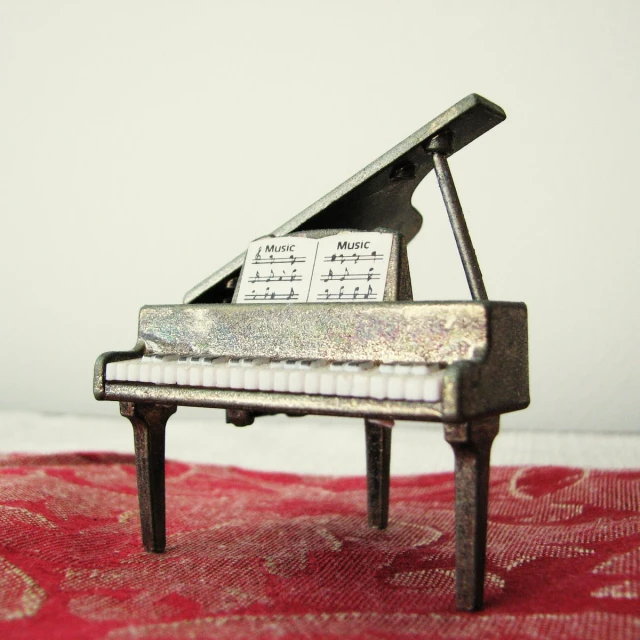 the small, old piano is next to a red and white carpet