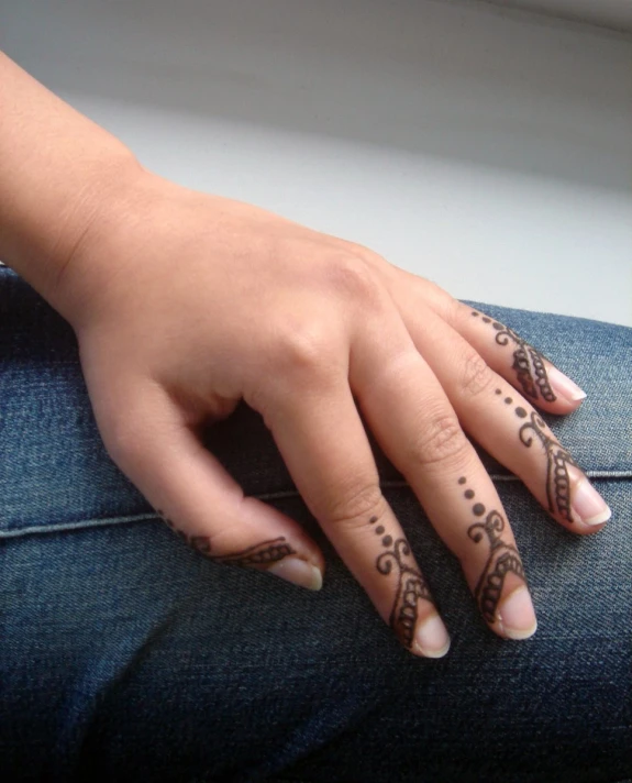 a woman's hands with hendid tattoos on their fingers