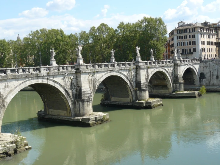 a stone bridge is seen over a green river