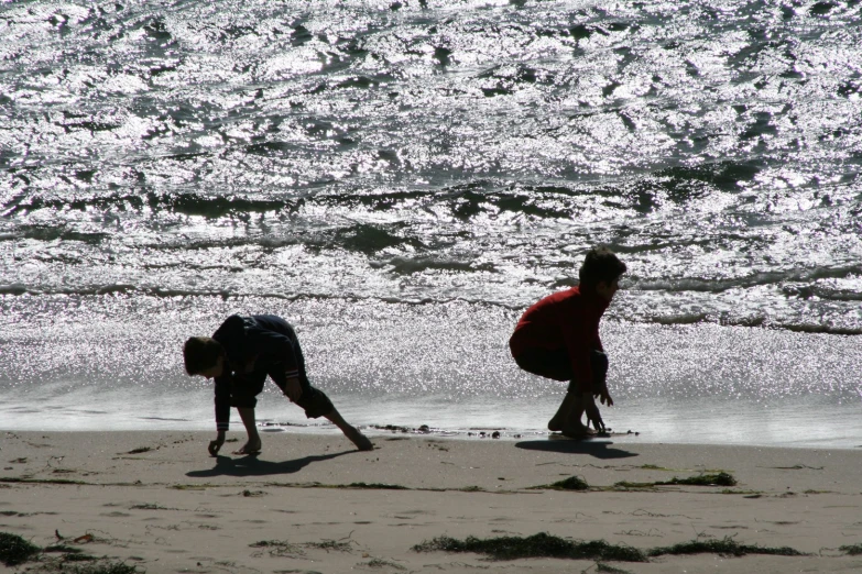 a pair of people with wetsuits walking along the beach