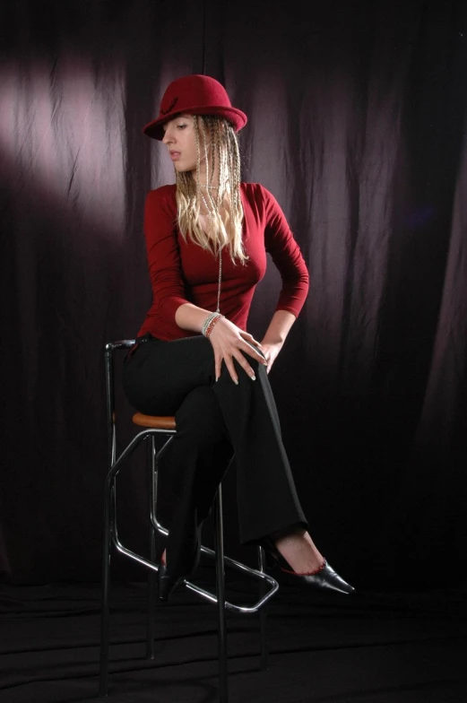 woman in red hat and black pants sitting on a chair