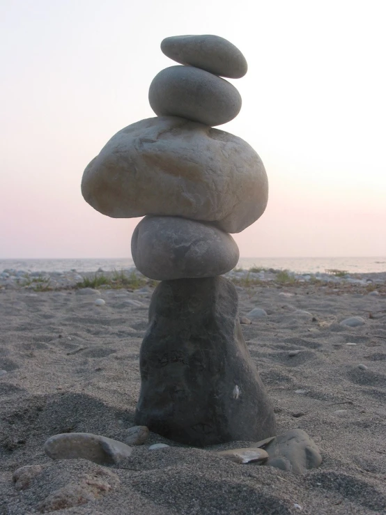 a stack of rocks with one on top in the sand