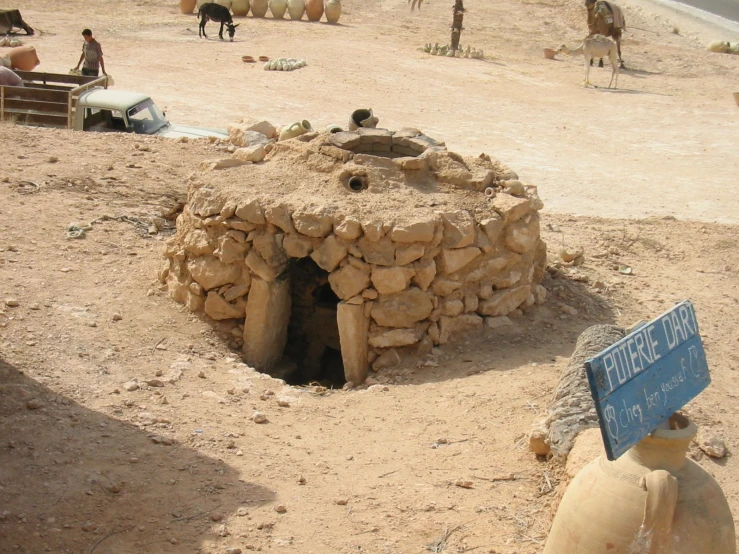 an old outhouse with people around it on a desert