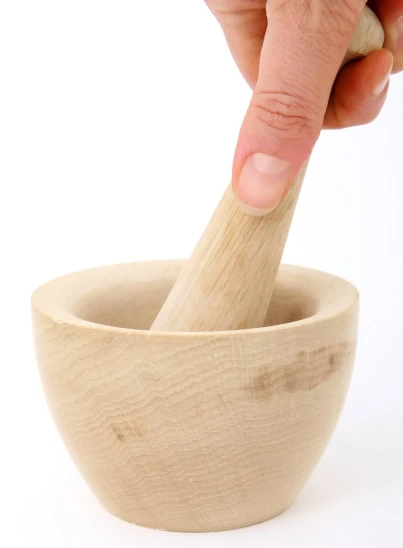 a person in a small wooden bowl using a wooden spoon