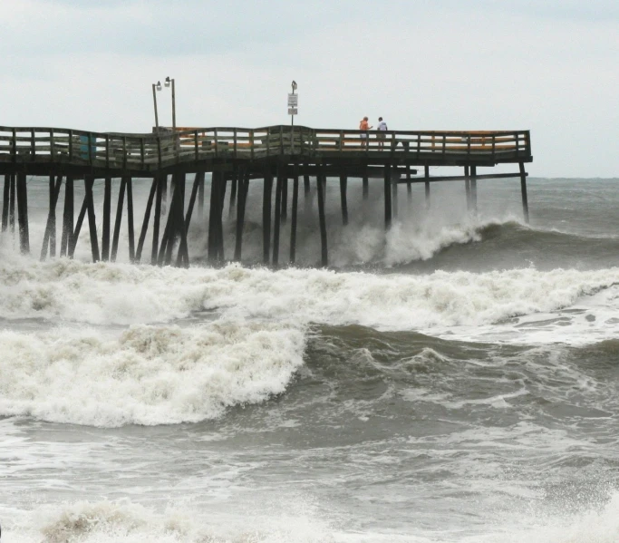 a pier on top of a body of water with crashing waves